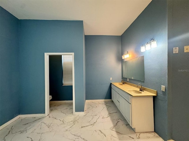 bathroom featuring marble finish flooring, baseboards, and toilet