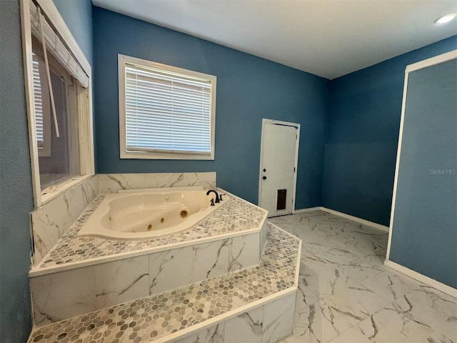 bathroom with marble finish flooring, a whirlpool tub, and baseboards