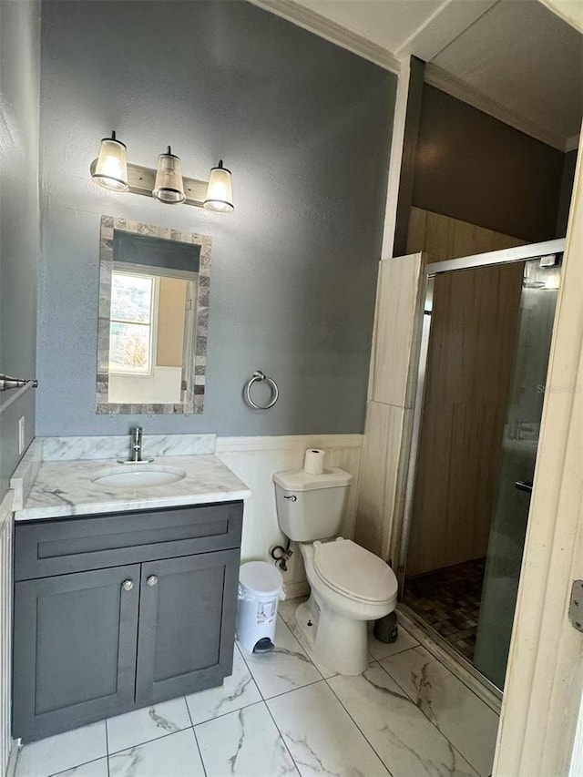 bathroom featuring marble finish flooring, a shower stall, a wainscoted wall, vanity, and toilet