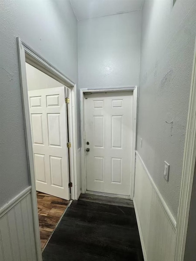 entryway featuring dark wood-style flooring and a wainscoted wall