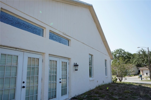 view of side of home featuring french doors and stucco siding