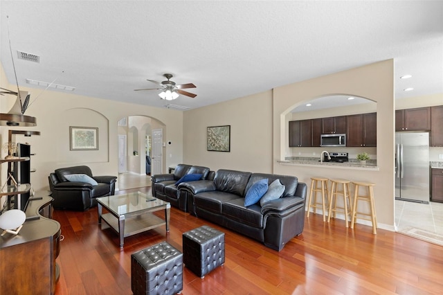 10837 Breaking Rocks Dr, Tampa, FL 33647 - living area with arched walkways, light wood-style floors, a ceiling fan, and recessed lighting