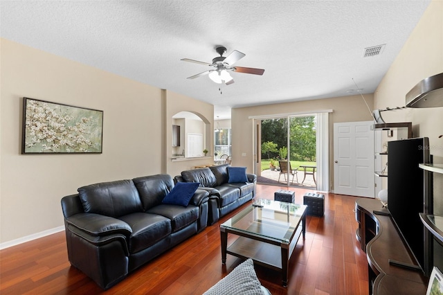 10837 Breaking Rocks Dr, Tampa, FL 33647 - living room featuring arched walkways, ceiling fan, dark wood-style flooring, a textured ceiling, and baseboards