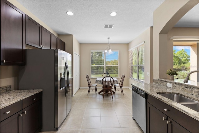 10837 Breaking Rocks Dr, Tampa, FL 33647 - kitchen with stainless steel appliances, a sink, dark brown cabinetry, light stone countertops, and baseboards