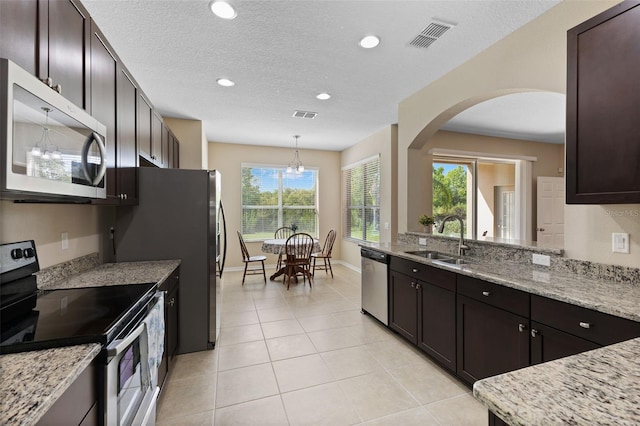 10837 Breaking Rocks Dr, Tampa, FL 33647 - kitchen featuring stainless steel appliances, a sink, arched walkways, light tile patterned floors, and recessed lighting