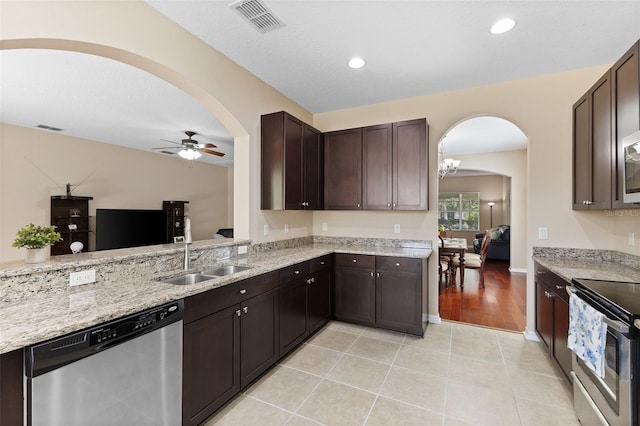 10837 Breaking Rocks Dr, Tampa, FL 33647 - kitchen with stainless steel appliances, arched walkways, a sink, dark brown cabinetry, and ceiling fan