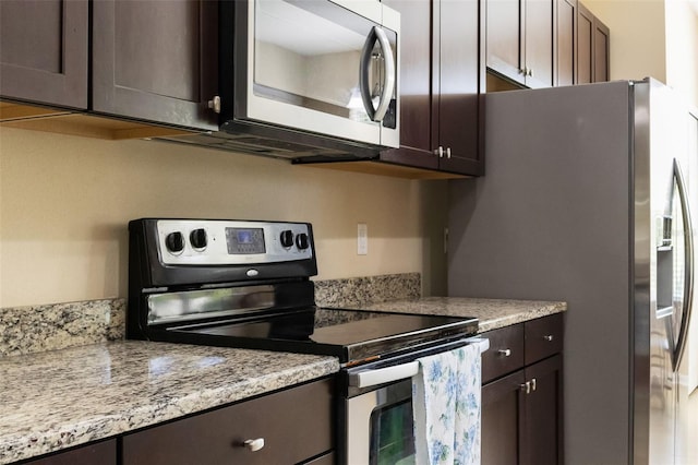 10837 Breaking Rocks Dr, Tampa, FL 33647 - kitchen with appliances with stainless steel finishes, dark brown cabinets, and light stone counters