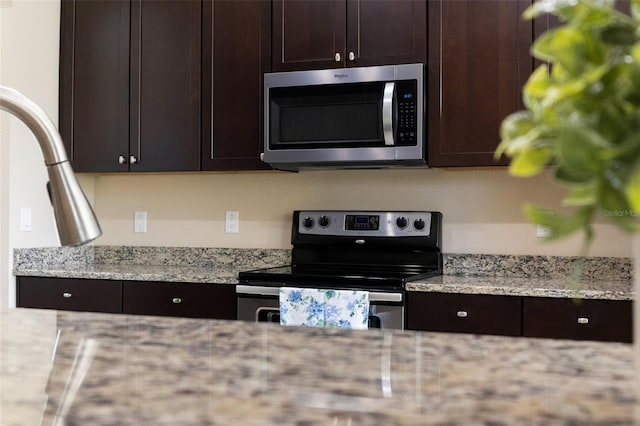 10837 Breaking Rocks Dr, Tampa, FL 33647 - kitchen featuring appliances with stainless steel finishes, dark brown cabinets, and light stone counters