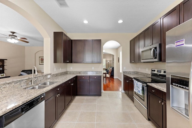 10837 Breaking Rocks Dr, Tampa, FL 33647 - kitchen with stainless steel appliances, a sink, a ceiling fan, light stone counters, and arched walkways