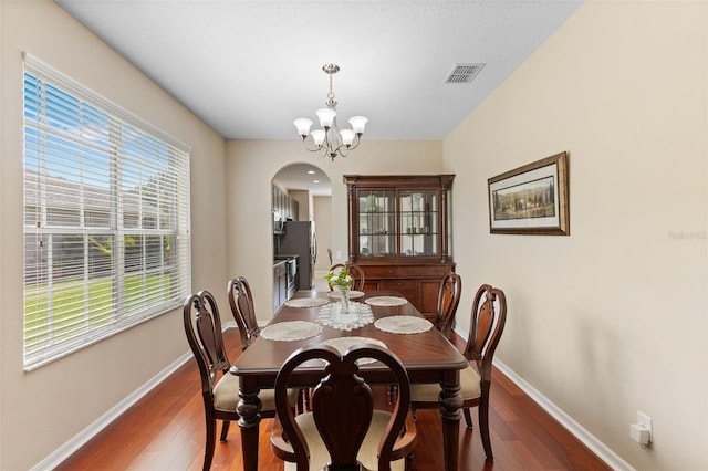 10837 Breaking Rocks Dr, Tampa, FL 33647 - dining space with arched walkways, wood finished floors, baseboards, and a chandelier