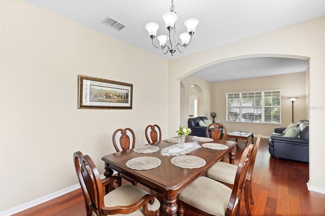 10837 Breaking Rocks Dr, Tampa, FL 33647 - dining space with arched walkways, a chandelier, wood finished floors, and baseboards
