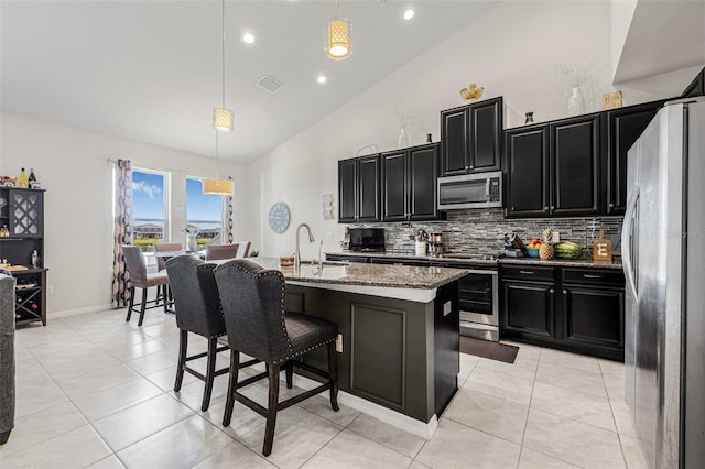 11917 Greenchop Pl, Riverview, FL 33579 - kitchen featuring stainless steel appliances, dark cabinetry, backsplash, an island with sink, and recessed lighting