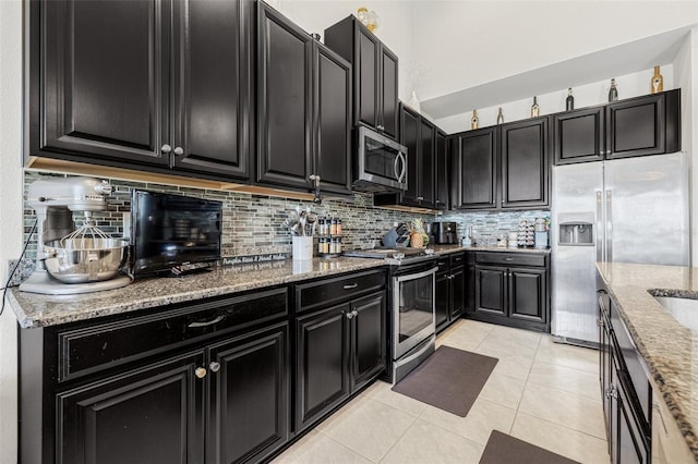 11917 Greenchop Pl, Riverview, FL 33579 - kitchen with stainless steel appliances, dark cabinets, decorative backsplash, light stone countertops, and light tile patterned flooring