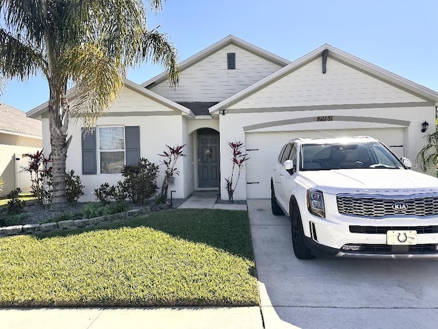2987 Neverland Dr, New Smyrna Beach, FL 32168 - view of front facade featuring a garage, driveway, a front lawn, and stucco siding