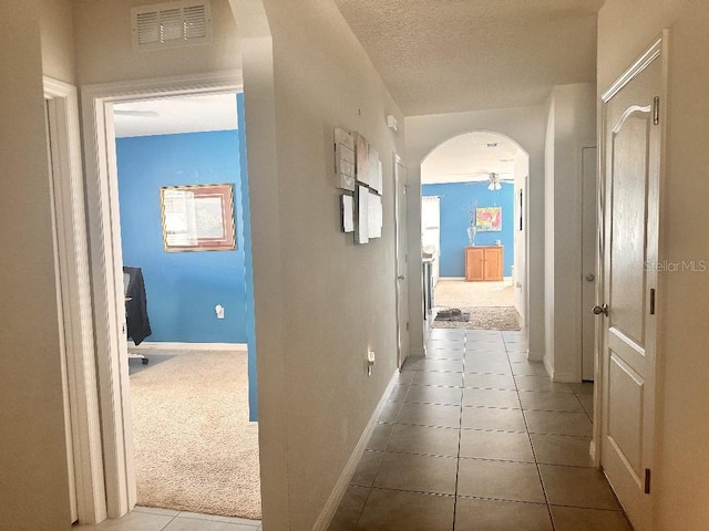2987 Neverland Dr, New Smyrna Beach, FL 32168 - hallway featuring arched walkways, tile patterned flooring, baseboards, and a textured ceiling