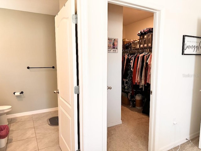 2987 Neverland Dr, New Smyrna Beach, FL 32168 - bathroom with baseboards, tile patterned floors, a spacious closet, and toilet