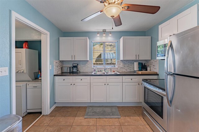 2035 29th Ave N, Saint Petersburg, FL 33713 - kitchen featuring stainless steel appliances, a sink, stacked washer / dryer, decorative backsplash, and white cabinetry