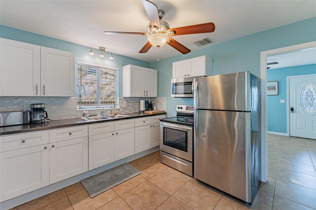 2035 29th Ave N, Saint Petersburg, FL 33713 - kitchen with stainless steel appliances, a sink, backsplash, dark countertops, and a ceiling fan