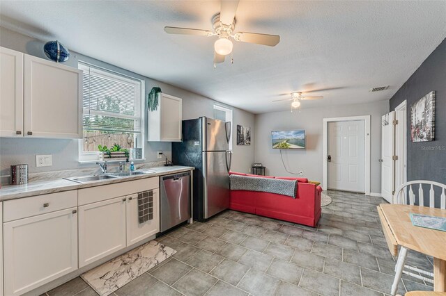 2035 29th Ave N, Saint Petersburg, FL 33713 - kitchen with stainless steel appliances, a ceiling fan, a sink, light countertops, and white cabinetry