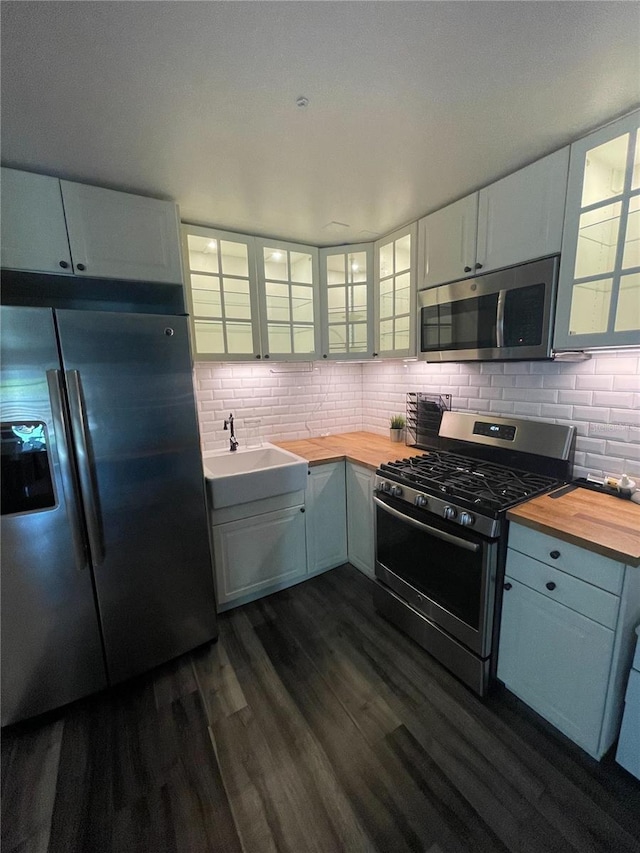 145 20th Ave SE, Saint Petersburg, FL 33705 - kitchen with stainless steel appliances, butcher block countertops, dark wood-style flooring, decorative backsplash, and glass insert cabinets