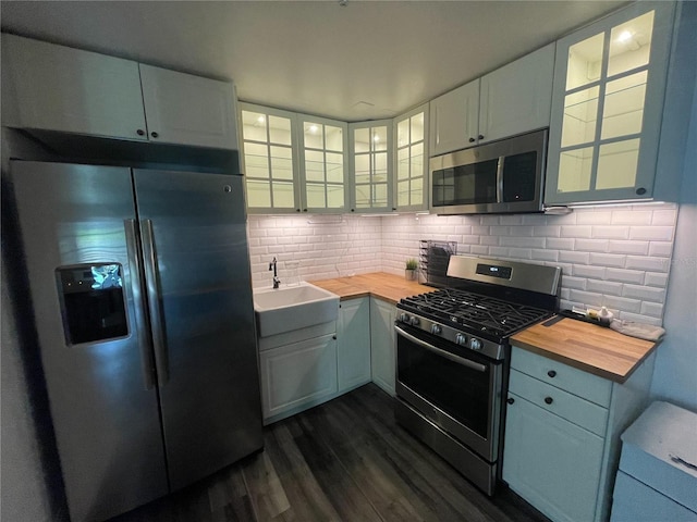 145 20th Ave SE, Saint Petersburg, FL 33705 - kitchen featuring appliances with stainless steel finishes, butcher block countertops, a sink, dark wood-style floors, and decorative backsplash