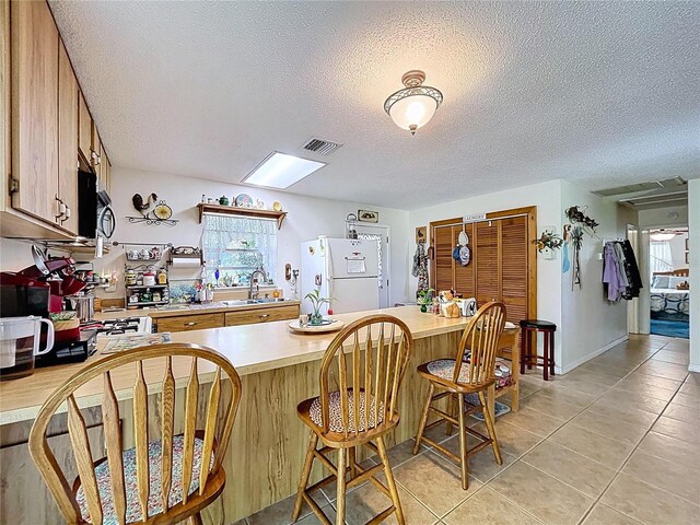 3544 Porter Rd, Lithia, FL 33547 - kitchen featuring freestanding refrigerator, light countertops, healthy amount of natural light, light tile patterned floors, and a textured ceiling