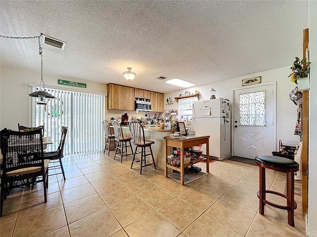 3544 Porter Rd, Lithia, FL 33547 - kitchen with freestanding refrigerator, stainless steel microwave, light tile patterned floors, a peninsula, and a textured ceiling