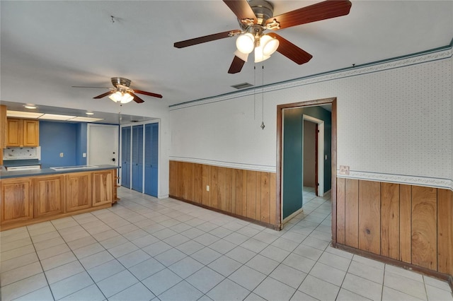 508 E Brentridge, Brandon, FL 33511 - kitchen with ceiling fan, a wainscoted wall, wooden walls, brown cabinets, and light tile patterned flooring