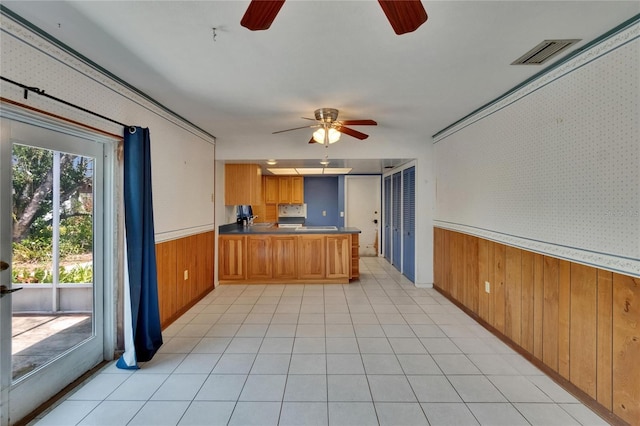 508 E Brentridge, Brandon, FL 33511 - kitchen with a ceiling fan, wood walls, a peninsula, brown cabinets, and wainscoting