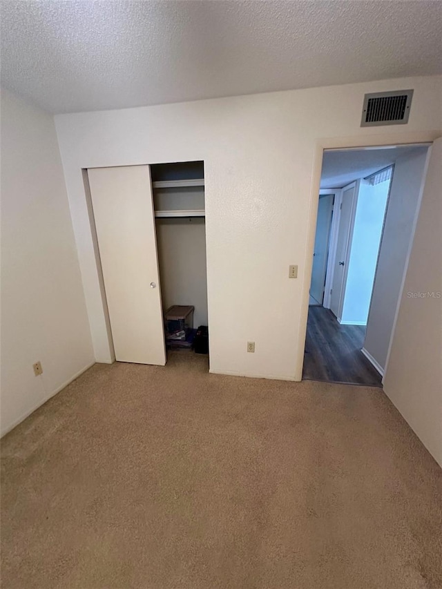 2360 Irish Ln Unit 16, Clearwater, FL 33763 - unfurnished bedroom featuring dark colored carpet, a closet, and a textured ceiling