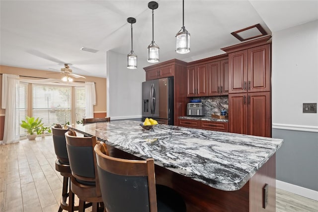 3413 W Kirby St, Tampa, FL 33614 - kitchen with stainless steel fridge with ice dispenser, a kitchen breakfast bar, light stone counters, pendant lighting, and a kitchen island