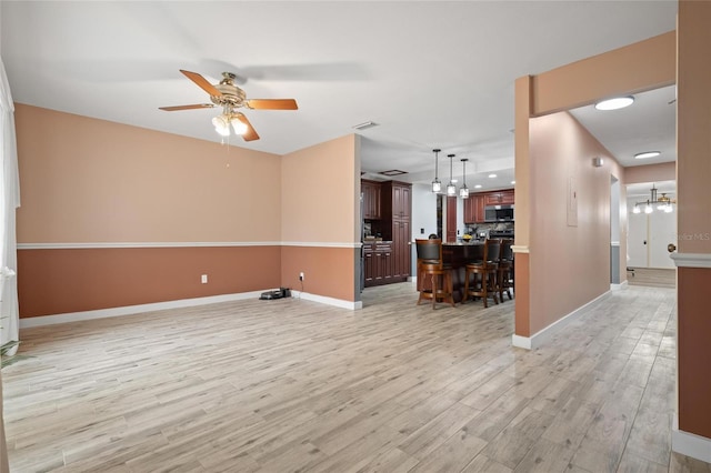 3413 W Kirby St, Tampa, FL 33614 - unfurnished living room with ceiling fan, light wood finished floors, baseboards, and a chandelier