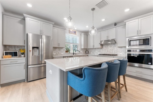 412 S Albany Ave Unit 2, Tampa, FL 33606 - kitchen with stainless steel appliances, under cabinet range hood, a center island, light wood-style floors, and recessed lighting