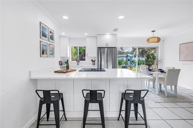 3843 Neptune Dr SE, Saint Petersburg, FL 33705 - kitchen with freestanding refrigerator, a breakfast bar, white cabinets, a peninsula, and light countertops