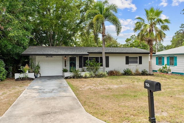 single story home with a garage, concrete driveway, a front yard, and stucco siding