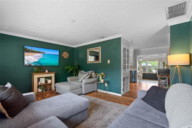 living area featuring wood finished floors, baseboards, and crown molding