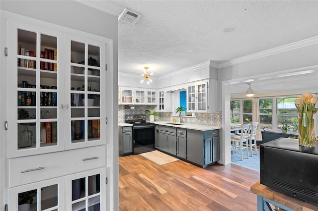 kitchen featuring stainless steel electric range oven, gray cabinetry, a textured ceiling, crown molding, and tasteful backsplash