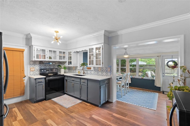kitchen featuring black electric range oven, a sink, light countertops, gray cabinets, and light wood finished floors