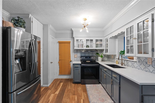 kitchen with stainless steel fridge with ice dispenser, black / electric stove, a sink, light wood-style floors, and light countertops