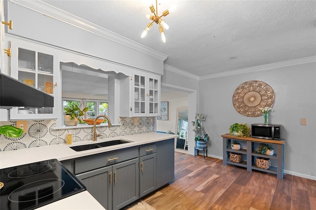 kitchen with stainless steel microwave, backsplash, ornamental molding, light countertops, and a textured ceiling