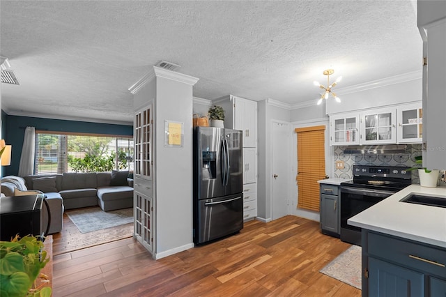 kitchen with stainless steel fridge with ice dispenser, electric range, light countertops, wood finished floors, and crown molding