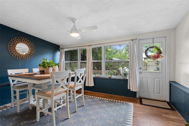 dining area with wood finished floors, ceiling fan, and a textured ceiling