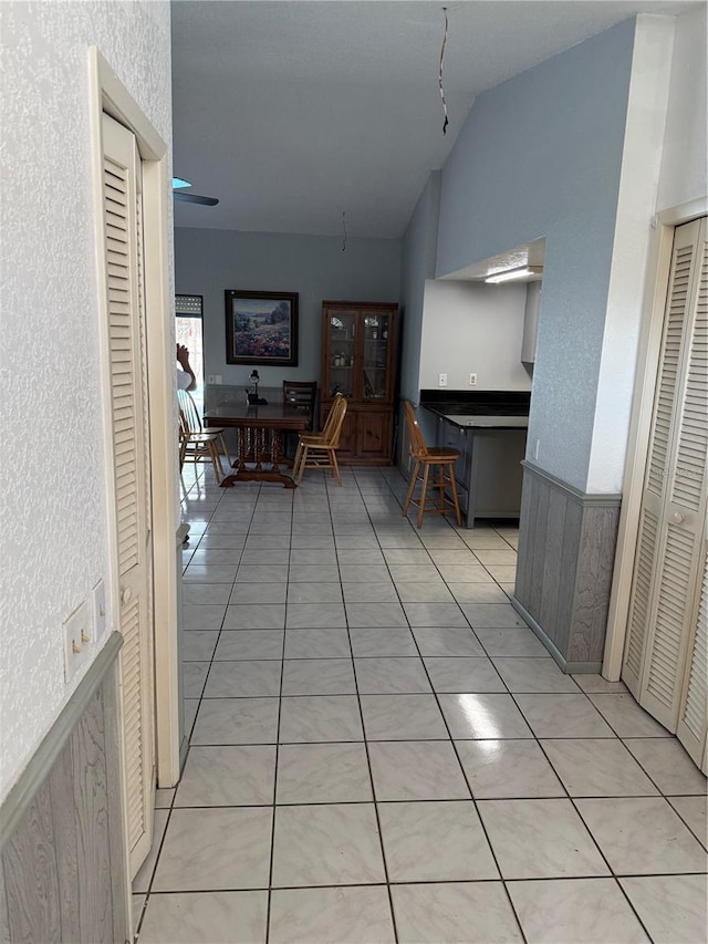 2026 Aaron Pl, Clearwater, FL 33760 - hallway featuring vaulted ceiling, light tile patterned floors, a wainscoted wall, and a textured wall