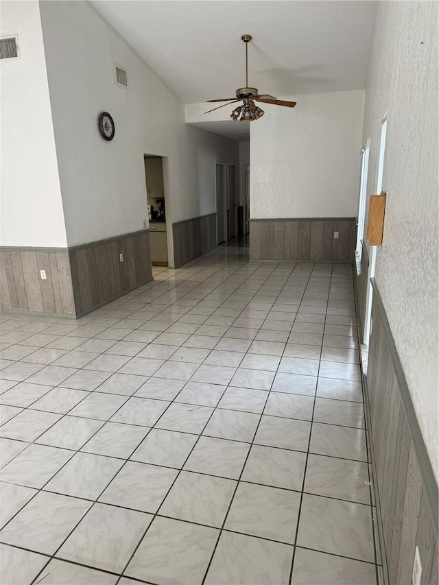 2026 Aaron Pl, Clearwater, FL 33760 - empty room featuring ceiling fan, wainscoting, vaulted ceiling, and wood walls