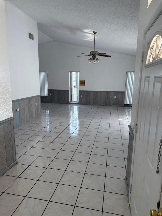 2026 Aaron Pl, Clearwater, FL 33760 - unfurnished room featuring wainscoting, a ceiling fan, wooden walls, a textured ceiling, and light tile patterned floors