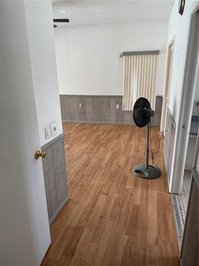2026 Aaron Pl, Clearwater, FL 33760 - spare room featuring wood finished floors, a ceiling fan, wainscoting, a textured ceiling, and a textured wall