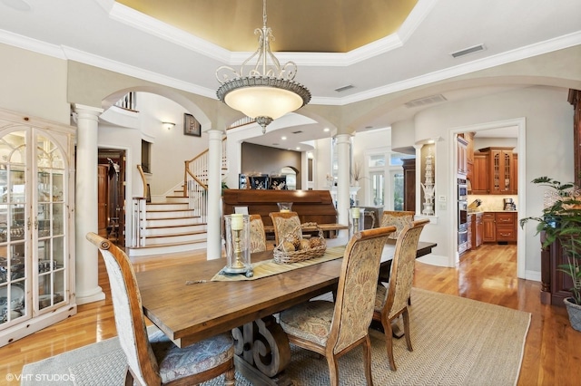 919 Ballinger Rd, Lutz, FL 33548 - dining space featuring decorative columns, a tray ceiling, arched walkways, and ornamental molding