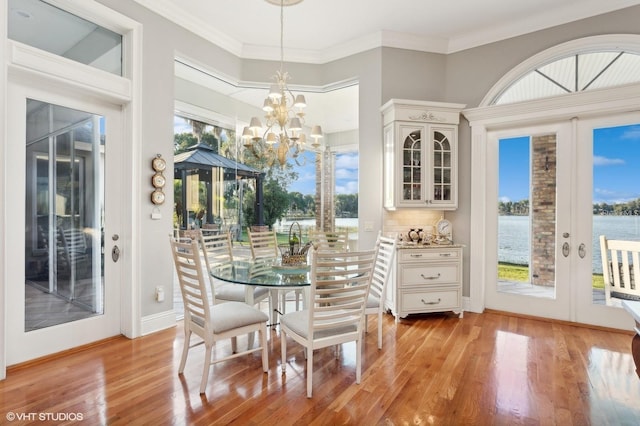 919 Ballinger Rd, Lutz, FL 33548 - dining room featuring light wood-style floors, french doors, a chandelier, a water view, and crown molding