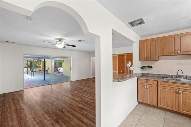 903 Tomahawk Trl, Brandon, FL 33511 - kitchen featuring a sink, dark stone counters, ceiling fan, open floor plan, and light wood-style floors