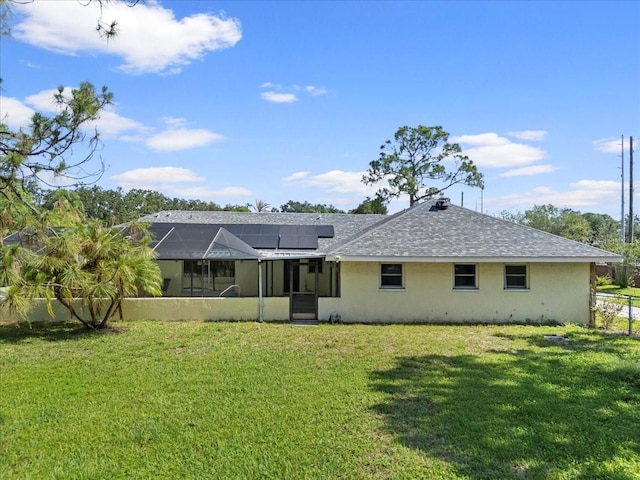 903 Tomahawk Trl, Brandon, FL 33511 - back of property featuring roof mounted solar panels, a lawn, stucco siding, and roof with shingles